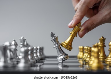 businessman hand moving gold Chess King figure and Checkmate enermy or opponent during chessboard competition. Strategy, Success, management, business planning, interruption and leadership concept