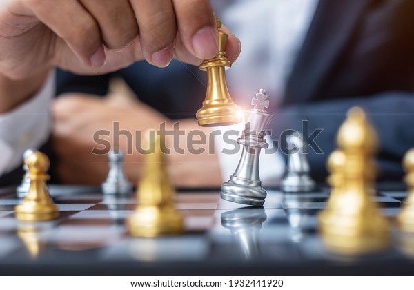 businessman\
hand moving gold Chess King figure and Checkmate opponent during\
chessboard competition. Strategy, Success, management, business\
planning, disruption and leadership\
concept