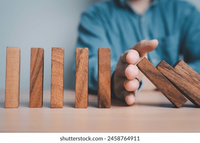 Businessman hand obstruct rectangle  block which falling to stop dominos others rectangle standing for risk assessment and crisis management concept.