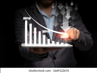 Businessman Hand Point Drawing Decrease Trend Arrow For Economic Crisis In 2020 On Black Background. It Is Symbol Of Business Investment Down From Trade War And Coronavirus (COVID 19).