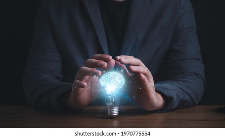 Businessman hand protecting with lightbulb with virtual brain glowing , patent and creative idea innovation concept.