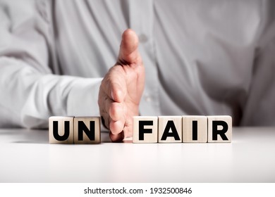 Businessman hand puts away the first two letters from the word unfair and transforms it into fair. Justice and fairness in business concept.