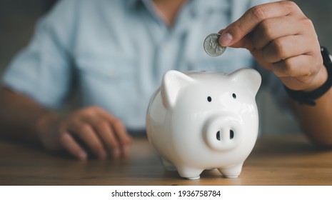 businessman hand putting coin in piggy bank. Saving money concept, business finance and investment.