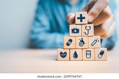 Businessman  hand stacking  healthcare icons on wooden block cube for health insurance and life assurance concept. - Powered by Shutterstock