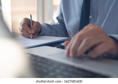 Businessman hand touching on touchpad, typing on laptop computer keyboard, writing on notebook. Corporate man, accountant online working in modern office. Business and technology concept - Shutterstock ID 1627681600