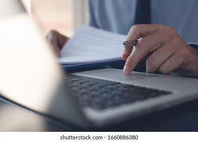 Businessman Hand Touching On Touchpad, Typing On Laptop Computer Keyboard, Reading Business Document. Corporate Man, Lawyer Working In Modern Office. Business And Technology Concept