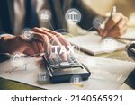Businessman hand using calculator and writing make note with calculate about finance accounting.Financial research,government taxes and calculation tax return concept.Tax and Vat concept.