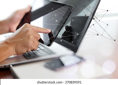 Businessman hand using laptop and mobile phone with social network diagram on wooden desk as concept