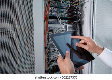 Businessman Hand Using Tablet Computer In Modern Server Room