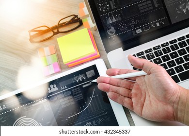 businessman hand working with digital tablet computer and memo note and laptop  with business strategy layer effect on wooden desk as concept