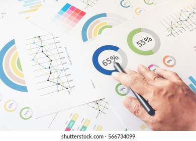 businessman hand working on wooden desk in office and there are many documents, graphs. Can be attributed to financial articles. - Shutterstock ID 566734099