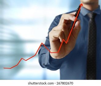 Businessman Hand Writing A Business Graph On A Glass Wall 