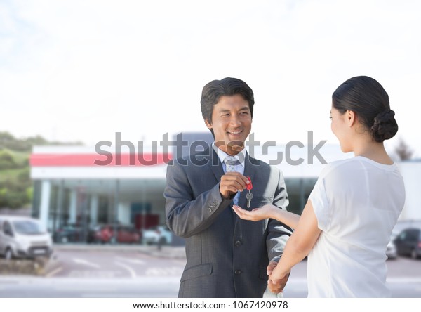 Businessman\
handing car keys to woman at car auto\
store