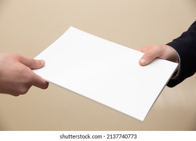 Businessman Handing Over A Paper Document To A Fellow Employee Or Customer. Concept On The Topics: Exchange Of Information, Conclusion Of A Contract, Transfer Of Documents.