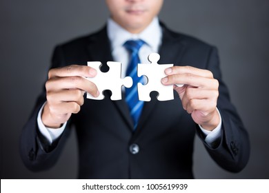 Businessman hands connecting puzzle pieces representing the merging of two companies or joint venture, partnership, Mergers and acquisition concept. - Shutterstock ID 1005619939