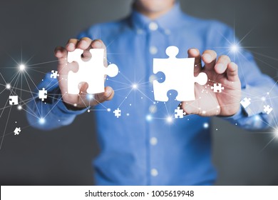 Businessman hands connecting puzzle pieces representing the merging of two companies or joint venture, partnership, Mergers and acquisition concept. - Shutterstock ID 1005619948