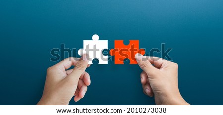 Businessman hands connecting puzzle pieces representing the merging of two companies or joint venture, partnership, Mergers and acquisition concept