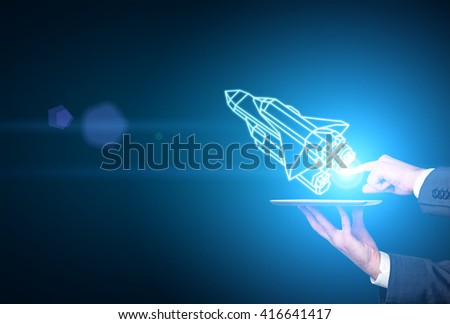 Businessman hands holding tablet with abstract rocket ship on blue background. Start up concept