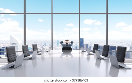 A Businessman With Hands On The Back Of His Head Sitting In A Chair At The Head Of A Big Table In A Meeting Room And Looking Into A Panoramic Window. Paris. Back View. Concept Of Relaxation