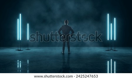 Businessman with hands on hips facing neon blue light panels in dark, foggy room. Futuristic atmosphere