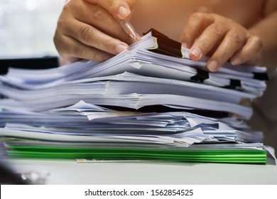 Businessman hands searching unfinished documents stacks of paper files on office desk for report papers, piles of sheet achieves with clips on table, Document is written, drawn,presented.