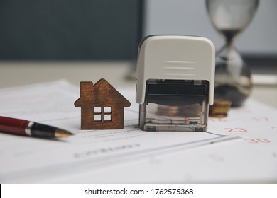 Businessman hands signing documents file paperwork financial or property mortgage real estate investment business on desk office with chart report document contact customer with wooden house models. - Shutterstock ID 1762575368
