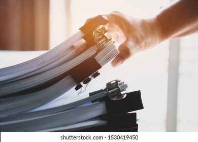 Businessman hands working in stacks documents of paper files, searching information on desk office, Accounting budget report file, check working for arranging unfinished of paperwork on busy office