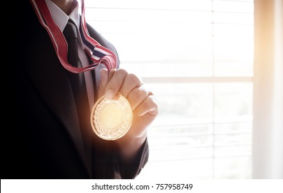 Businessman Hanging Around Neck With Gold Medals In Hands With Smart Suit. Concept For Success And Winning In Business.