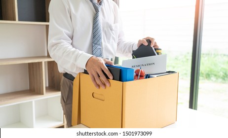 businessman has a brown cardboard box and resignation letter write reason for resigning from work or unemployment and change job concept
