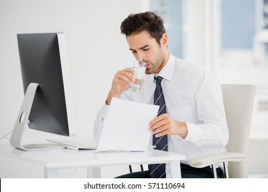 Businessman having a glass of water while working in office