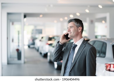 Businessman Having A Phone Call At The Car Showroom, Car Dealership Concept