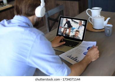 Geschäftsmann in Kopfhörern spricht mit Kollegen über Videoanrufe beim Online-Briefing während der Selbstisolation und Quarantäne. Webcam-Gruppenkonferenz mit Kollegen auf Laptop zu Hause.