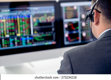 Businessman in a headset looking at the statistics of stock exchange, view over the shoulder - Powered by Shutterstock