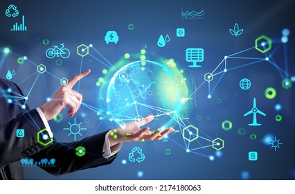 Businessman hold and finger touch earth sphere hologram, glowing eco hud with diverse icons. Ecosystem and future technology. Concept of renewable sources - Powered by Shutterstock - Get 15% off with code: PIKWIZARD15