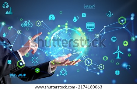 Businessman hold and finger touch earth sphere hologram, glowing eco hud with diverse icons. Ecosystem and future technology. Concept of renewable sources