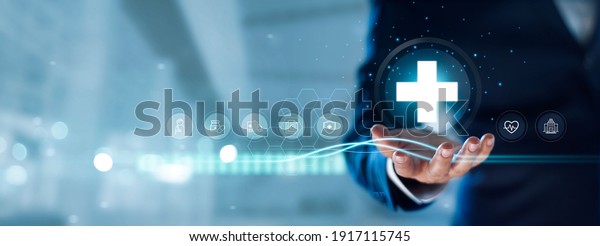 Businessman hold virtual medical network\
connection icons. Covid-19 pandemic develop people awareness and\
spread attention on their healthcare, rising growth in hospital and\
health insurance\
business.