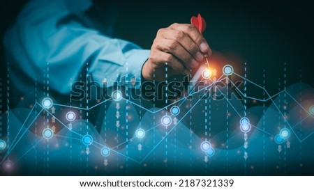 Businessman holding arrow pointing to graph, goal setting ideas and business strategies. through planning and teamwork To analyze and develop company performance from growth data to the future.
