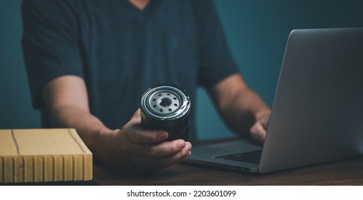 Businessman holding automotive oil filter in hand and buying on online marketing website and social media store form laptop computer.