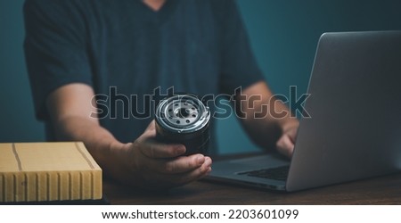 Businessman holding automotive oil filter in hand and buying on online marketing website and social media store form laptop computer. Foto d'archivio © 