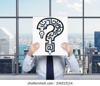 Businessman is holding a banner with the Maze in a shape of Question mark. City view background.  - Powered by Shutterstock