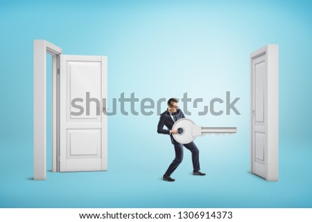 Businessman holding big key between an open door and a closed one on blue background. Business and management. Way to success. Taking chances.