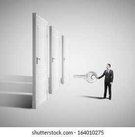 Businessman Holding Big Key With Closed Doors