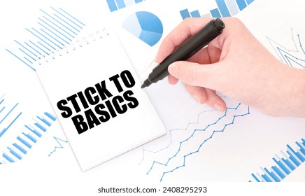 Businessman holding a black marker, notepad with text STICK TO BASICS, business concept
