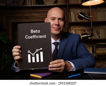 Businessman Holding A Blank Notepad. Business Concept About Beta Coefficient With Phrase On The Sheet.
