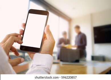 Businessman Holding Blank Screen Smart Phone In Meeting Room.