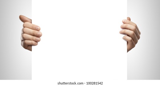 Businessman holding a blank white board. Male hands holding a blank white panel. On a gray background - Powered by Shutterstock