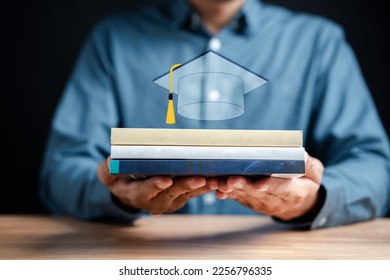 Businessman holding book stack with graduation cap icon. Reading for university education course degree, study knowledge to creative thinking idea and problem solving solution. - Shutterstock ID 2256796335