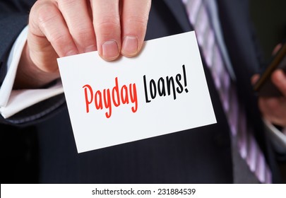 A businessman holding a business card with the words, Payday Loans, written on it.