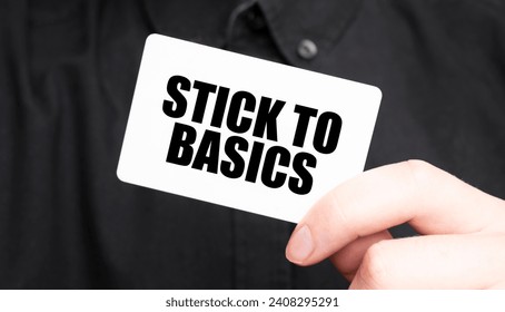 Businessman holding a card with text STICK TO BASICS, business concept