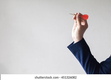 Businessman holding a dart aiming at the target - business targeting, aiming, focus concept.